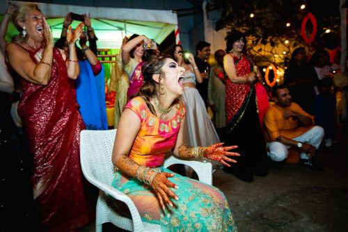 Bride reacting with surprise and laughter during groom’s performance at sangeet in Pune wedding