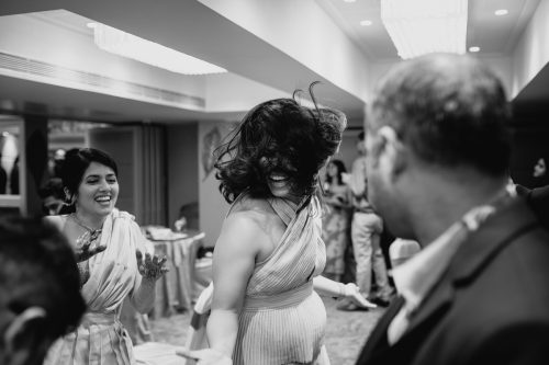 Guests dancing wildly with hair flying during cocktail party in Pune wedding black and white photo