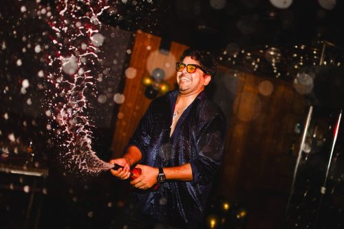 Groom spraying champagne during cocktail party celebration at Pune wedding