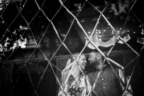 Bride and groom reflected through glass during creative black and white couple portrait - maharashtrian groom & Belgian bride in Pune