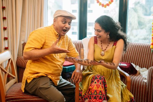 Father reacting with surprise to bride’s mehendi as she laughs during wedding at pyc Pune