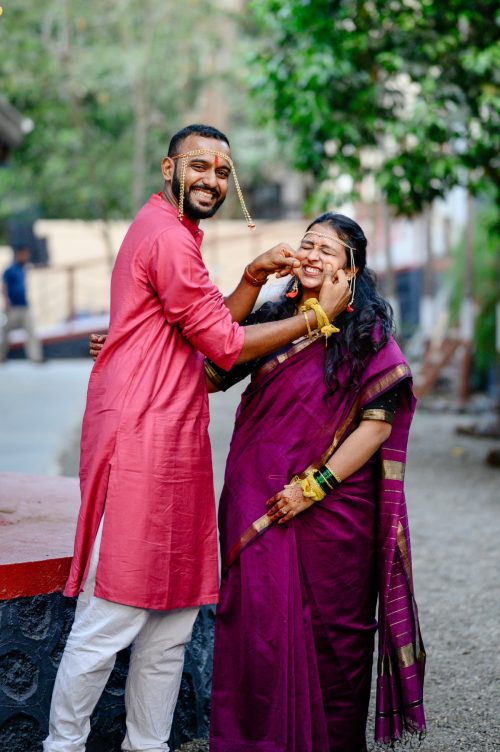 Groom playfully pulling bride’s cheeks during maharashtrian wedding candid couple portraits at dhepe vada, pune