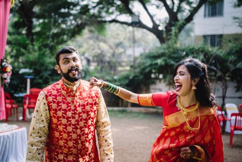 Bride playfully punching groom during candid wedding couple portraits at a maharashtrian wedding, digambar hall, pune