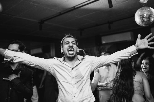 Groom dancing with arms wide open during cocktail party in Pune wedding black and white photo