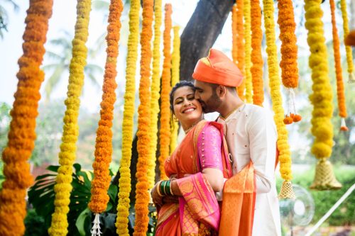 Bride and groom embracing during Maharashtrian wedding couple portraits with marigold decorations at Keshav baug, pune