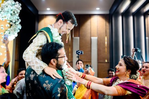 a fun moment between groom and bride as they exchange garlands during mangalashtaka during maharashtrian wedding ceremony