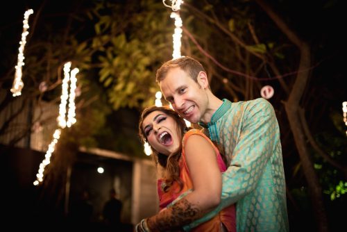 Bride and groom laughing together during sangeet night couple portraits