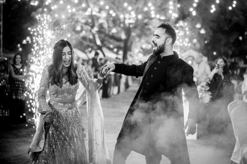 Bride and groom entering sangeet with pyro lights and holding hands at Keshavbaug Pune wedding