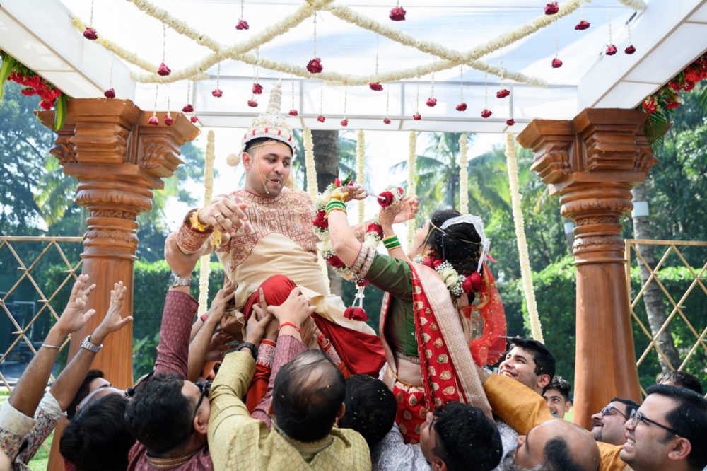 Bengali Groom lifted by friends during garland exchange as Maharashtrian bride tries to reach him during fun wedding ritual at Pandit Farms Pune