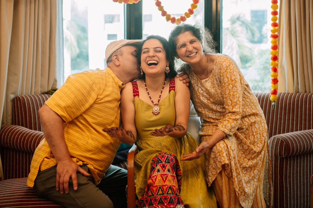 Bride laughing as her parents hug her during mehendi ceremony at Oakwood PYC Pune
