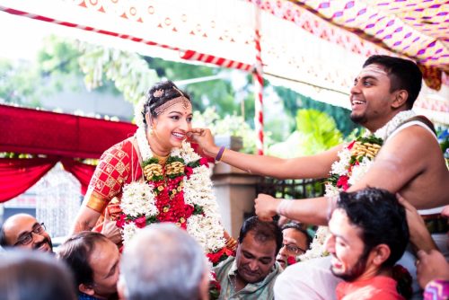 happy moment during garland exchange during a tam bram wedding in pune as groom holds the bride cheeks and she smiles looking at him